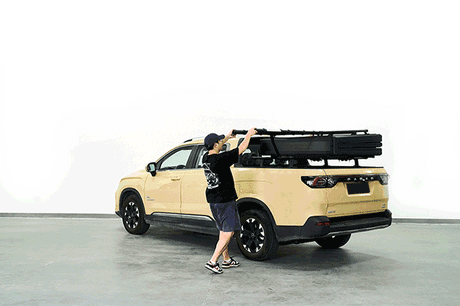 Person setting up rooftop tents on a beige vehicle for outdoor adventure