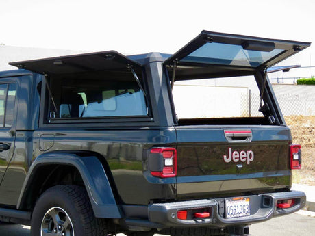 Jeep Gladiator showcasing off-road capabilities with open tailgate in a scenic environment.