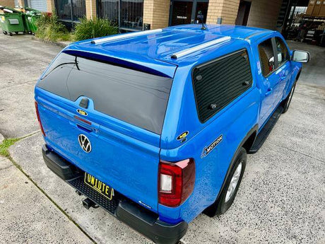 Blue Volkswagen with a Dual Cab Canopy parked in front of a building.
