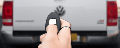 Person using remote to activate TAILGATE CENTRAL LOCKING system on a 4x4 vehicle, enhancing security and convenience.