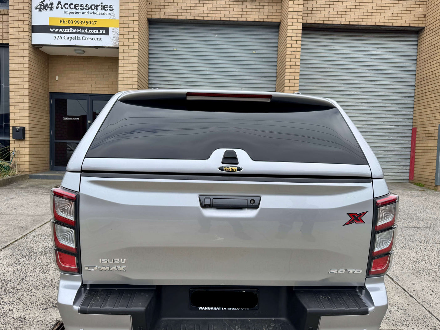 Rear view of silver Isuzu D-Max fitted with canopy DMax 2020-2025 FORCE PRO by UniUte in front of garage.