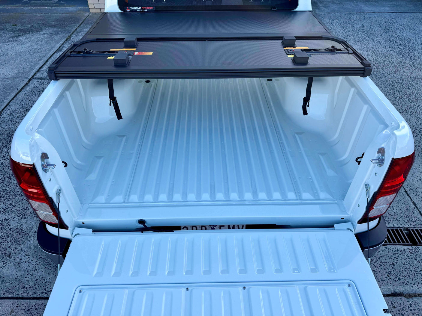 Mitsubishi Triton MV with tri-fold hard tonneau cover open, showing spacious truck bed. Tonneau cover mitsubishi triton for secure cargo storage.