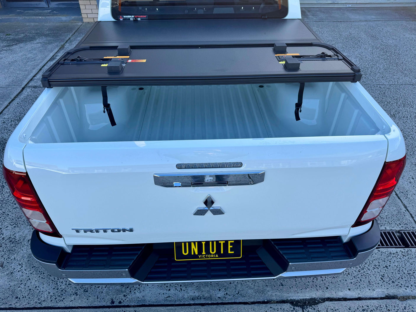 Tonneau cover Mitsubishi Triton MV 2024+ tri-fold hard lid on white truck bed, providing secure and stylish cargo protection