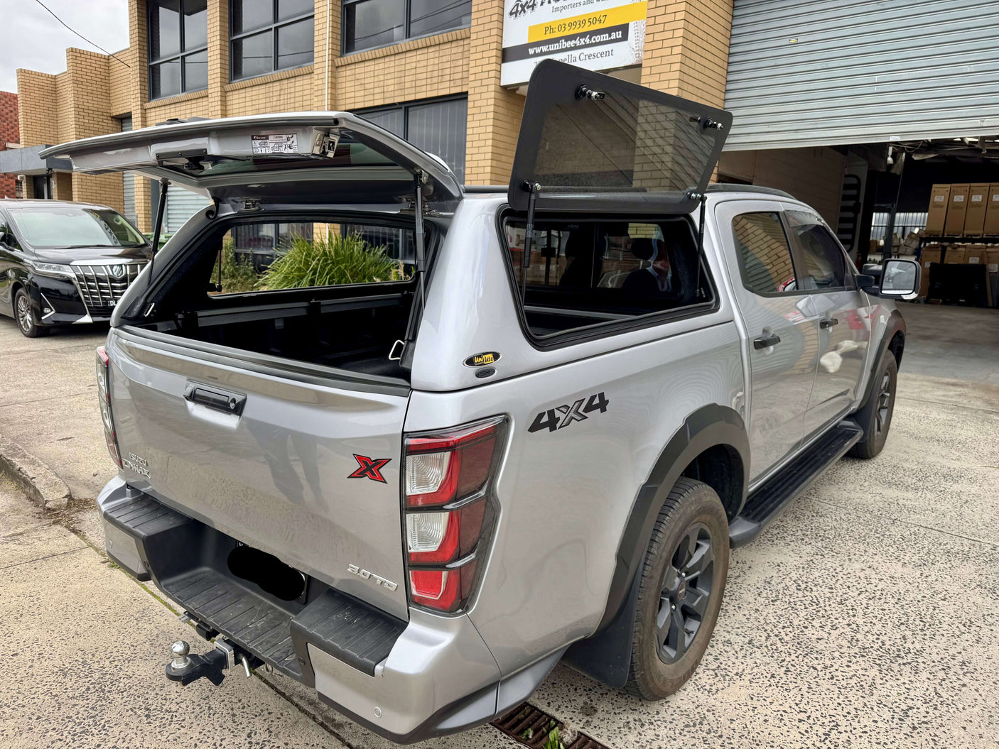 Silver Isuzu D-Max with FORCE PRO canopy dmax upgrade parked outside industrial building.