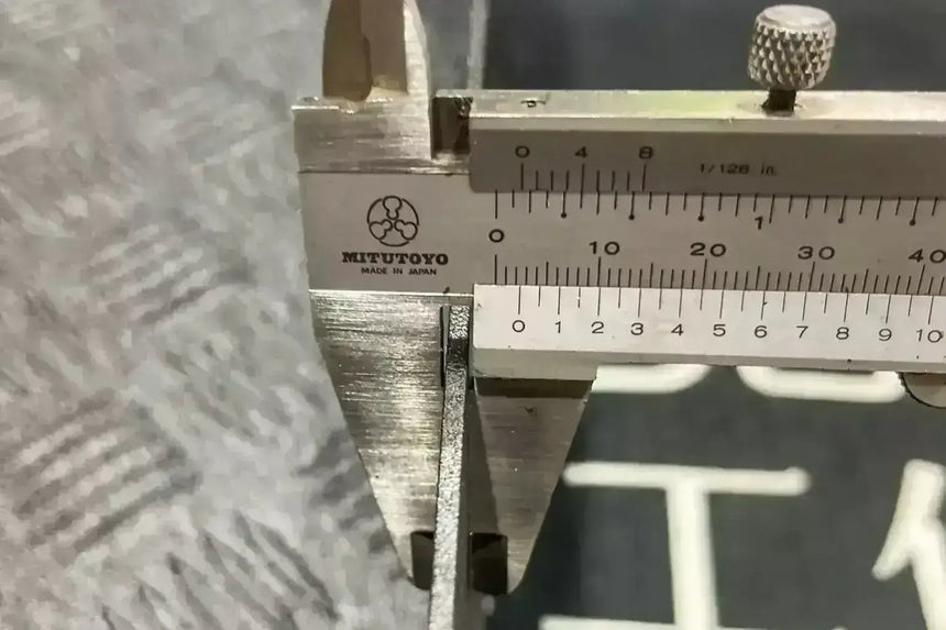 Close-up of calipers measuring metal thickness for cargo tray construction precision