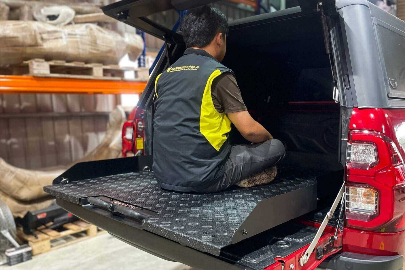 Person using ute slide tray in Toyota Hilux, showcasing UniUte Sliding Tray Drawer for models 2004-2025.