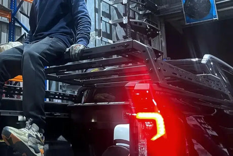 Person seated on a ute with a tub rack for hauling gear, highlighting its versatility and rugged design for carrying tools and camping equipment.