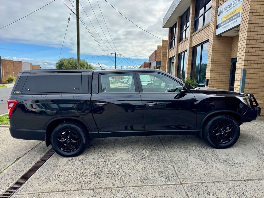 Black KGM Musso Canopy XLV 2018-2025 with stainless steel ute canopy parked outside an industrial building.