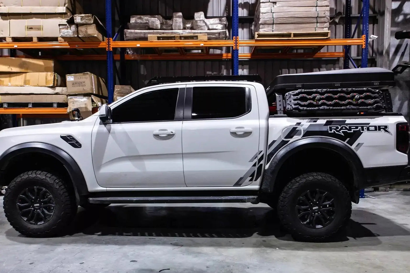 White pickup truck with tub rack carrying gear in a warehouse