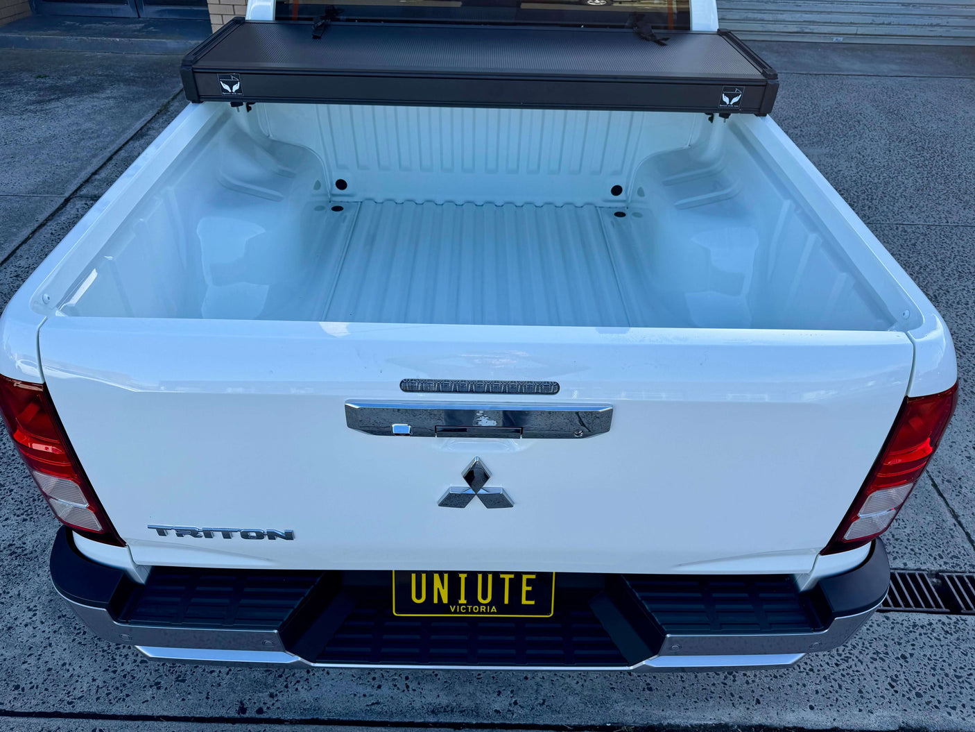 Open truck bed showing tonneau cover Mitsubishi Triton MV tri-fold hard lid, showcasing cargo space protection.