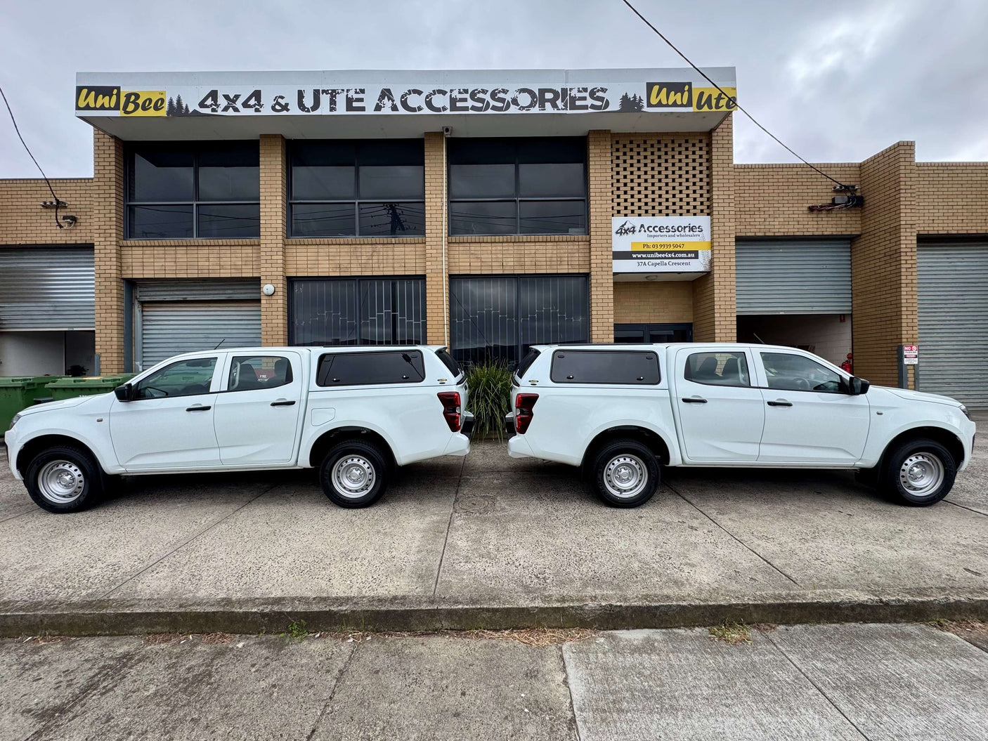 Dual white Isuzu D-Max trucks with Force Pro canopy in front of 4x4 accessory store, showcasing canopy DMax 2020-2025.