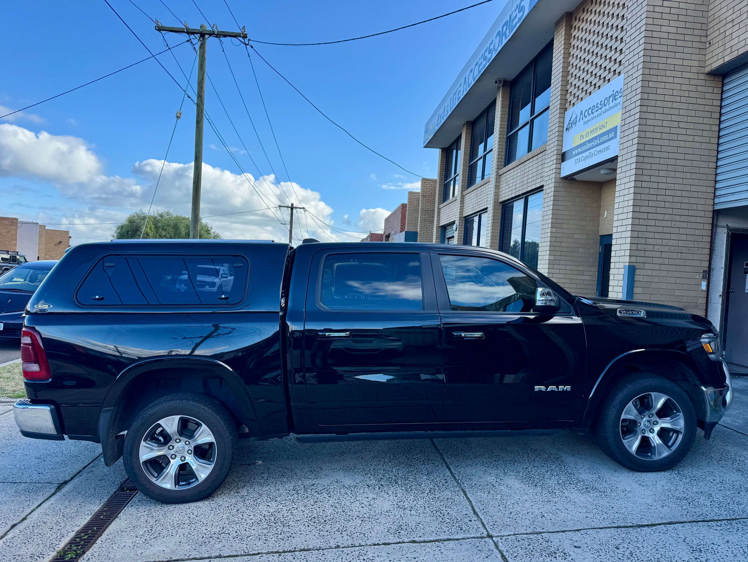 Black RAM 1500 canopy parked outside an industrial building, showcasing durability and style.
