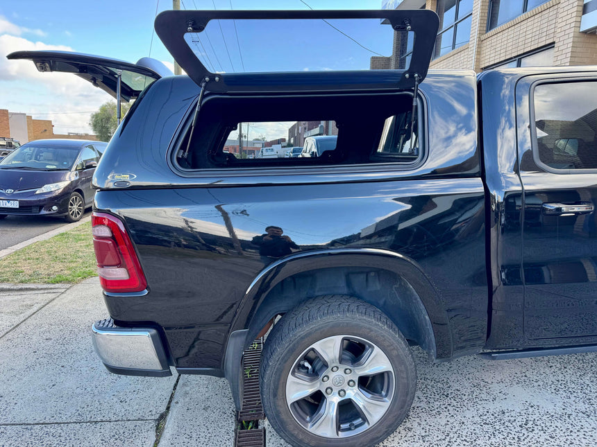 Black RAM 1500 canopy for DT 2020-2025, rear view showcasing durability in an urban setting.