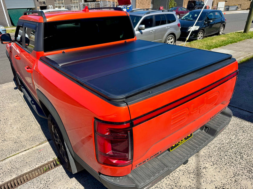 BYD Shark 6 hard lid 2025+ tri-fold cover installed on red ute, enhancing style and security.