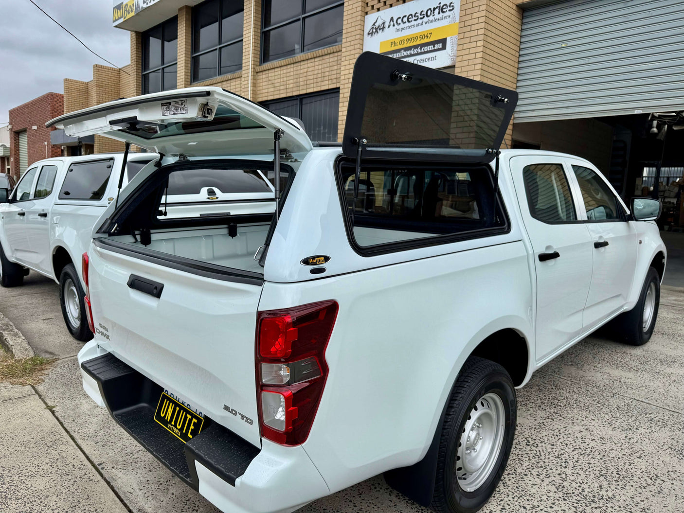 Canopy DMax 2020-2025 Isuzu FORCE PRO by UniUte installed on a white pickup truck outside a workshop.