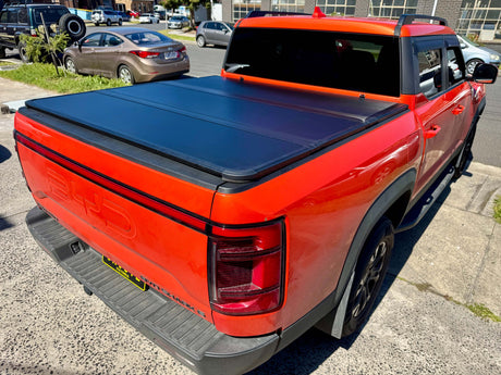 Red BYD Shark 6 with hard lid tri-fold cover, showcasing the BYD Shark 6 hard lid for 2025+ models, parked outdoors.