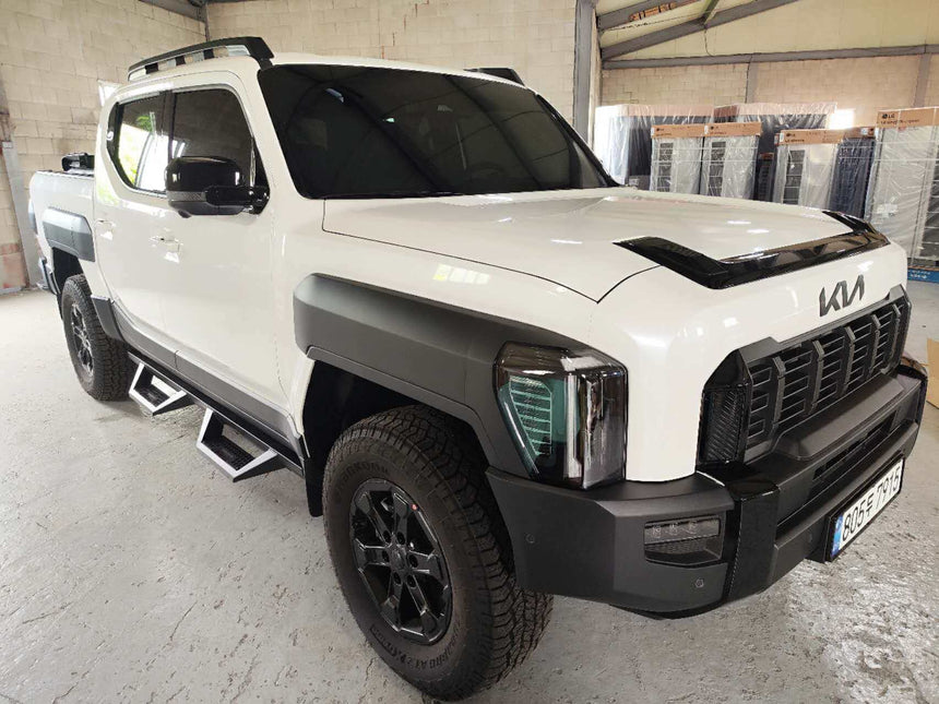 White KIA truck with black kia tasman side steps in a garage, featuring upgraded style and functionality.