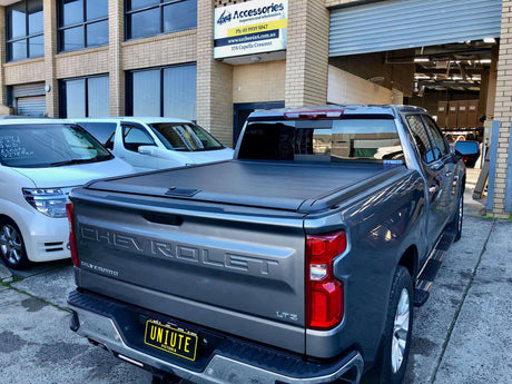 Chevrolet Silverado 1500 with UniUte Gen2 Manual Roller Shutter, parked in front of a store, showcasing silverado 1500 roller shutter.