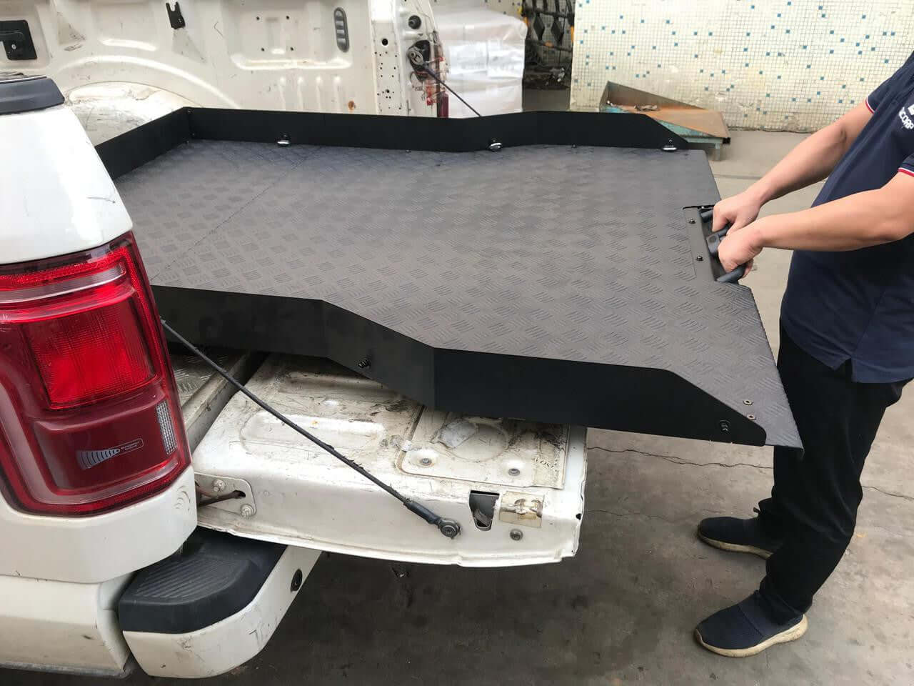 Person installing slide out tray in Ford F-150 truck bed, enhancing storage accessibility with UniUte sliding tray drawer system.