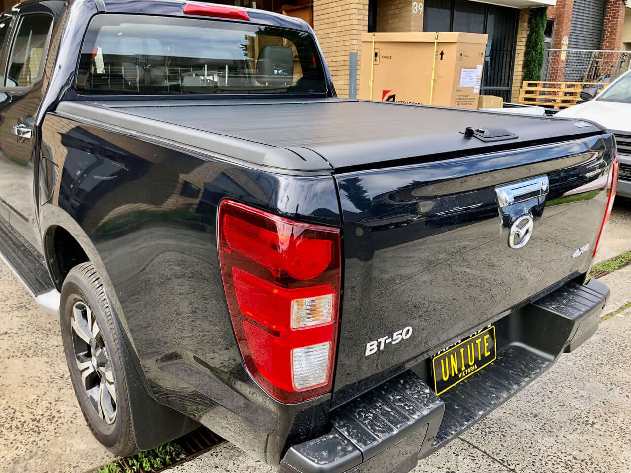 Isuzu D-Max with electric roller shutter — urban setting parked rear view