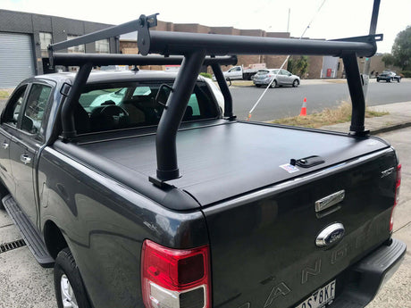 Black ute with ladder racks for Gen1 & Gen2 roller shutters on top, parked on an industrial street.