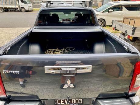 Open Triton roller lid on Mitsubishi truck showcasing versatile truck bed space