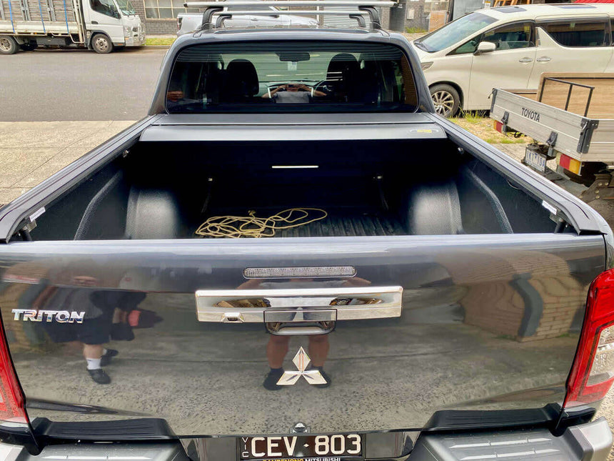Open Triton roller lid on Mitsubishi truck showcasing versatile truck bed space
