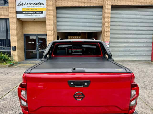 UniUte Gen2 manual roller shutter for Nissan Navara NP300 demonstrating cargo protection on a red truck.