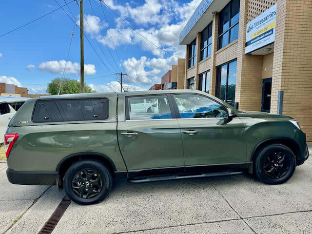 Green SsangYong Musso XLV with canopy for ssangyong musso parked outside building