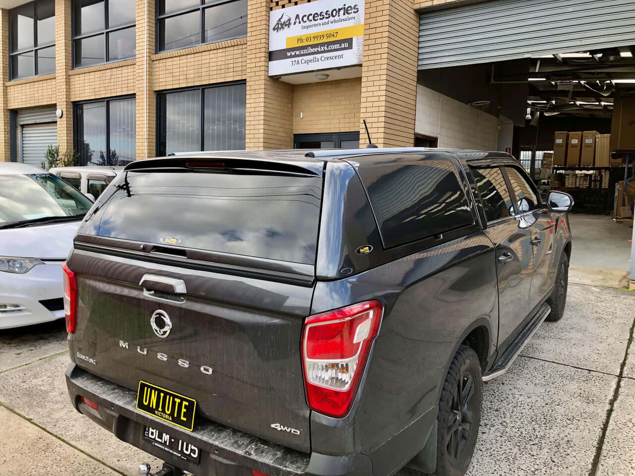 Black SsangYong Musso XLV Canopy FORCE PRO PLUS in front of a modern building