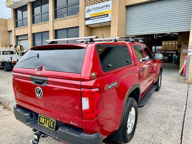 Red Volkswagen Amarok Canopy 2023 model in front of a building, showcasing amarok canopy by UniUte.