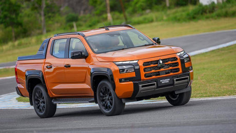 Orange Mitsubishi Triton 2024 driving on a track, showcasing design features