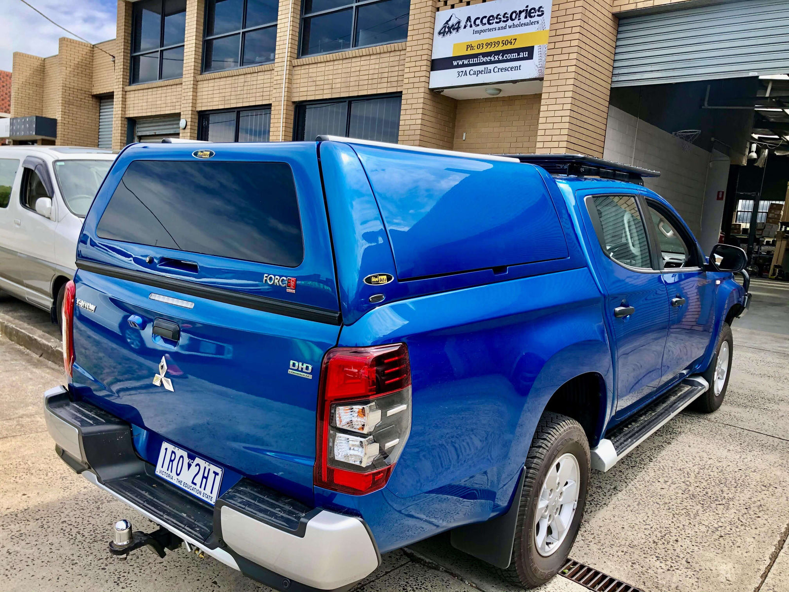 Blue pickup truck featuring canopies for Triton parked outside a garage