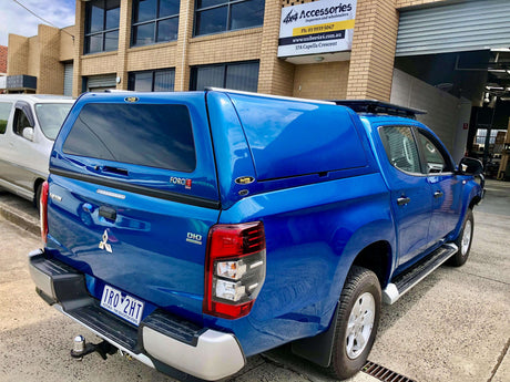 Blue pickup truck featuring canopies for Triton parked outside a garage
