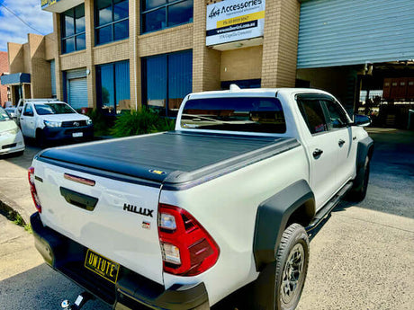 Toyota Hilux GR Sport 2024 parked outside a service center, showcasing its sleek rear design.