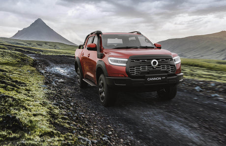 Red GWM Cannon Ute accessories driving off-road in scenic landscape