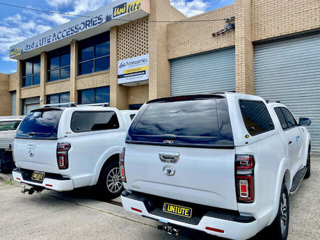 Two white utes with canopies parked outside an accessories store, highlighting Ute Canopy durability and functionality.
