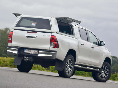 White truck with a canopy for Hilux parked on the road