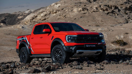 A red pick-up truck in a rocky desert landscape, showcasing essential accessories for utes.