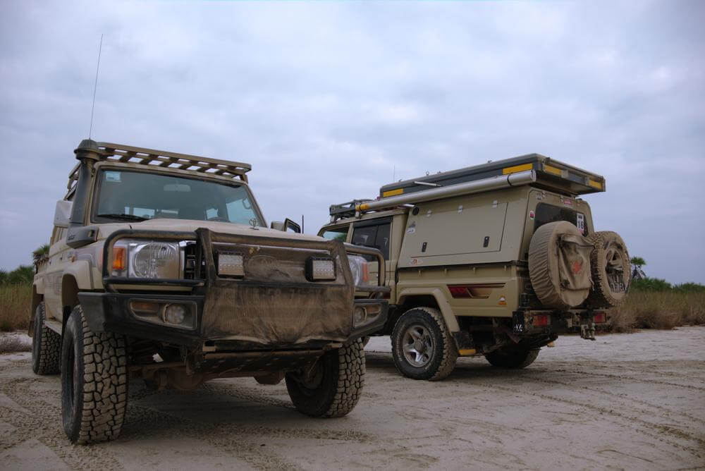 Off-road vehicles equipped with canopy roof bars for enhanced carrying capacity on a rugged terrain.