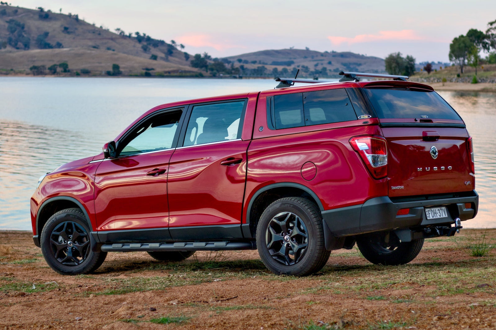 Red SsangYong Musso parked by a serene lake, showcasing ultimate style and functionality with ssangyong musso accessories.