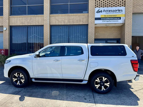 White vehicle with Fibreglass Ute Canopies parked outside an accessories shop.