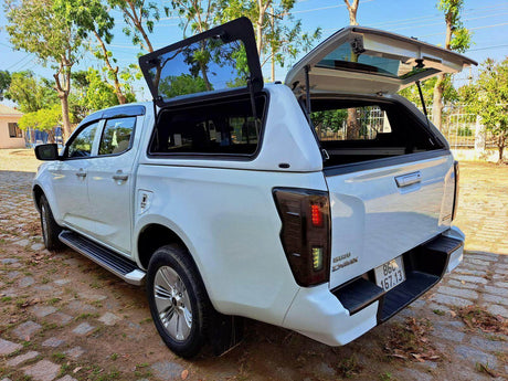White Ute with Fiberglass Canopies featuring open compartments, parked on a cobblestone path with trees in the background.