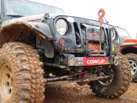 Mud-covered Jeep with 4x4 winch for off-road enthusiasts conquering challenging terrains.