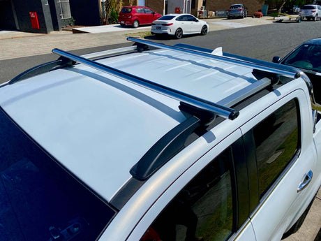 Rhino Rack installed on a white vehicle, showing roof-mounted load bars on a sunny day.