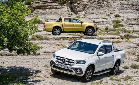 Two Mercedes-Benz X-Class 2018 pickup trucks parked on rocky terrain.
