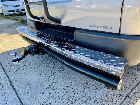 Red truck towing trailer with dirt bikes using UniUte tow bars for efficient transport.