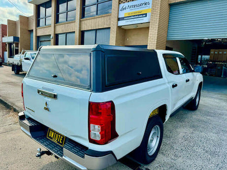 White Mitsubishi Triton accessories parked in front of a building