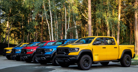 Colorful RAM 1500 trucks lined up in the forest showcasing RAM 1500 ACCESSORIES for powerful and stylish driving.