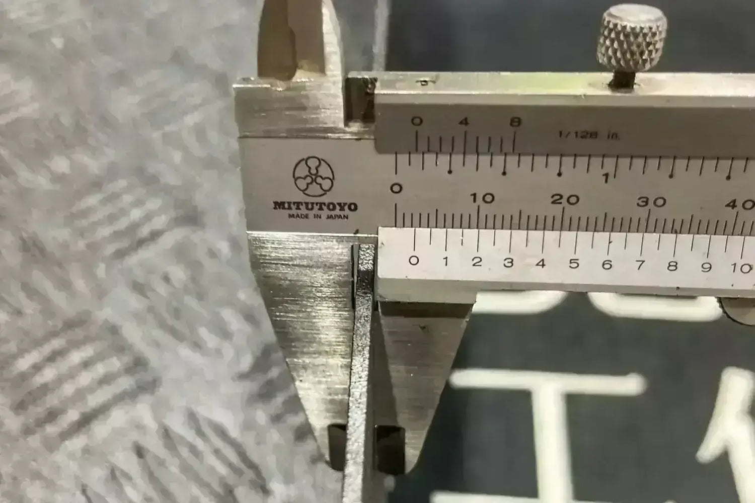 Close-up of calipers measuring metal thickness for cargo tray construction precision